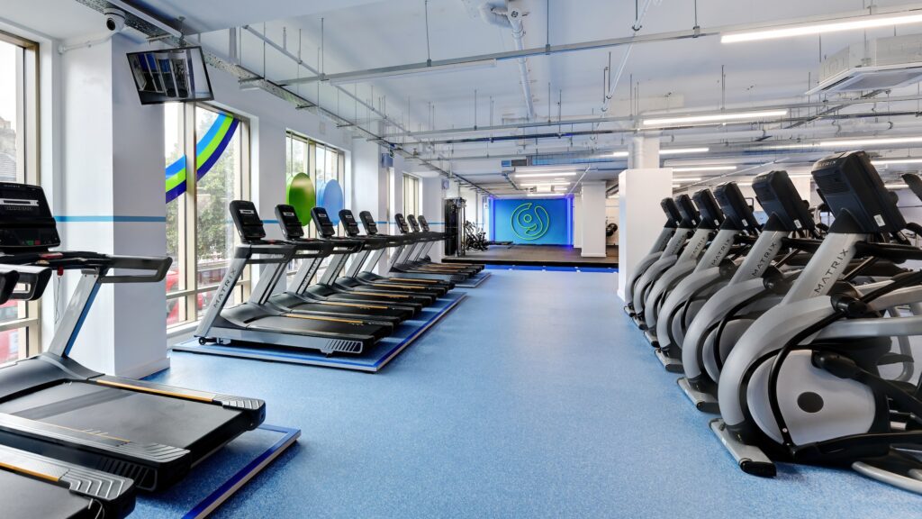 The Gym Group East Ham interior Design with cardio equipment along the wall and a large G logo at the end