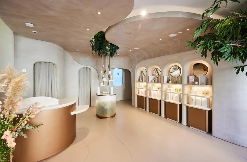 Sleek reception area in white and gold, featuring product display units and plant accents, creating a modern and luxurious atmosphere.