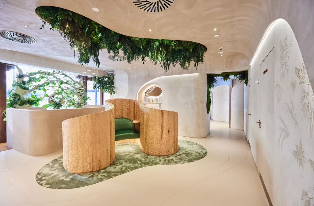 Individual private wooden seating with green cushions, positioned below a hanging plant ceiling feature, creating a cozy and natural atmosphere.
